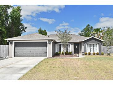 Charming single-story home with a two-car garage, landscaped yard, and gray stucco exterior at 3025 Bonkirk Dr, Deltona, FL 32738