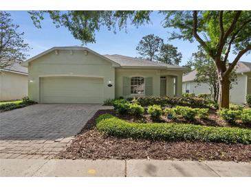 Charming single-story home featuring a two-car garage, brick driveway, and lush landscaping at 417 Victoria Hills Dr, Deland, FL 32724