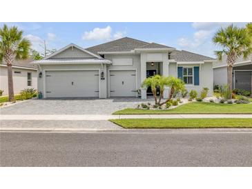 Beautiful single-story home featuring a well-manicured lawn, three-car garage, and charming landscaping with palm trees at 660 Mosaic Blvd, Daytona Beach, FL 32124