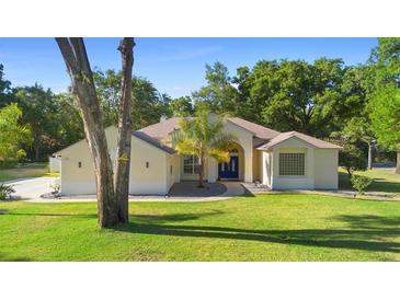 Inviting single-story home with a manicured lawn and blue front door, nestled in a lush, tree-filled landscape at 1523 Red Plum Holw, Deland, FL 32720