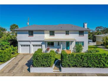 Charming two-story home boasts a crisp white facade, complemented by manicured greenery and a vibrant turquoise front door at 1613 Crescent Ridge Rd, Daytona Beach, FL 32118