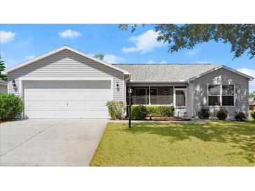 Charming single-story home with a well-manicured lawn and a two-car garage at 1930 Harston Trl, The Villages, FL 32162