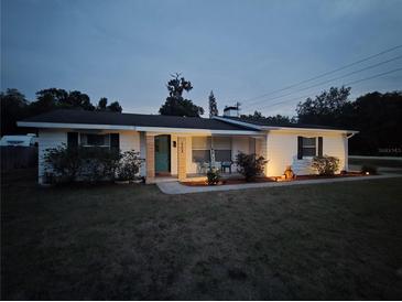 Charming single-story home with landscaped front yard and a welcoming porch at dusk at 2204 Poinsettia Dr, Deland, FL 32724