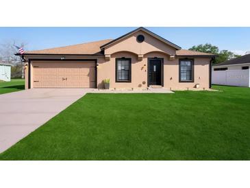 Charming single-story home featuring a well-manicured lawn, neutral paint, attached garage and a welcoming front entrance at 2448 Newmark Dr, Deltona, FL 32738