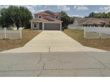 Charming two-story home with a concrete driveway and a lovely white picket fence at 2709 Sedgefield Ave, Deltona, FL 32725