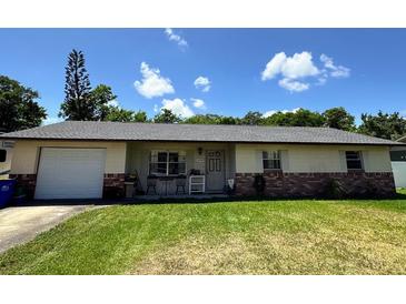Charming single-story home featuring a brick accent, a lush green lawn and mature landscaping at 2816 Travelers Palm Dr, Edgewater, FL 32141