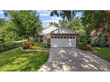 Charming brick home featuring a well-maintained lawn, mature landscaping, and an attached two-car garage at 30 Reflections Village Dr, Ormond Beach, FL 32174