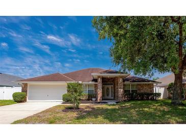 Charming single-story home with brick accents, a well-maintained lawn, and an attached garage at 5463 Carmody Lake Dr, Port Orange, FL 32128