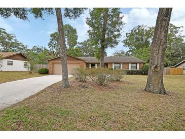 Charming one-story brick home featuring a large front yard with mature trees and a two-car garage at 1075 Burgoyne Rd, Deland, FL 32720