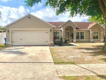 Charming single-story home with a well-manicured lawn, mature tree, and attached two-car garage at 1311 Fallwood Dr, Deltona, FL 32725
