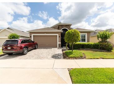 Charming single-story home featuring a well-manicured lawn, a brick driveway, and a two-car garage, perfect for suburban living at 2435 Pawtucket Pass, Mount Dora, FL 32757