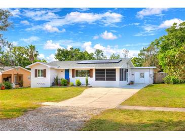 Charming single-story home with a well-manicured lawn, blue door, and solar panels under a bright blue sky at 738 Lindley Blvd, Deland, FL 32724