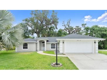 Charming single-story home boasts a manicured lawn, mature trees, and an attached two-car garage at 941 Pizarro Dr, Daytona Beach, FL 32119