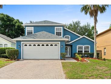 Charming two-story blue home with a manicured lawn, a brick driveway, and a two-car garage at 109 Fern Springs St, Debary, FL 32713
