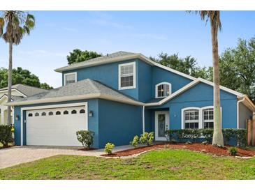 Charming two-story blue home with a manicured lawn, a brick driveway, and a two-car garage at 109 Fern Springs St, Debary, FL 32713