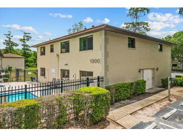 Exterior of a two-story condo building featuring a pool, black fence, and well-maintained landscaping at 1601 Big Tree Rd # 1302, South Daytona, FL 32119