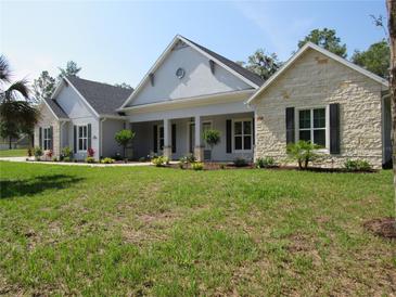 Beautiful single-story home featuring manicured landscaping, stone accents, and a welcoming covered porch at 1870 Pepper Tree Ln, Deland, FL 32720