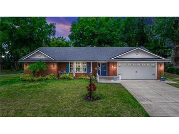Charming brick home featuring a manicured lawn, mature trees, and a two-car garage at 20 Monroe Ave, Debary, FL 32713