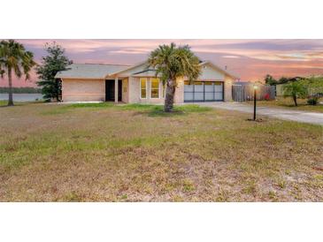 Charming brick home with a well-manicured lawn and a palm tree, located near a lake at 2055 Little Farms Ct, Deltona, FL 32738