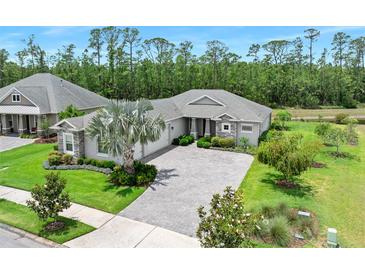 Beautifully landscaped front yard with paver driveway and mature palm tree at 3322 Modena Way, New Smyrna Beach, FL 32168