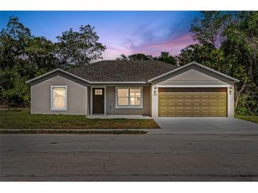 Charming single-story home featuring a well-maintained lawn and a two-car garage at dusk at 560 Sumner Ave, Orange City, FL 32763