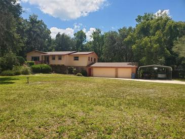 Charming two-story home with a large front yard, two car garage, and an attached car port at 1725 Turtle Hill Rd, Enterprise, FL 32725