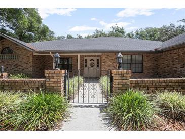 Charming brick home entrance with wrought iron gate and manicured landscaping at 3357 Black Willow Trl, Deland, FL 32724