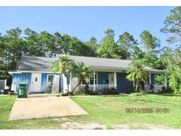 Charming single-story home featuring a covered porch, mature trees, and lush lawn at 3788 Fir Ct, Ormond Beach, FL 32174