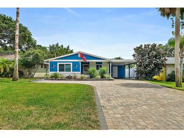 Charming blue home featuring a paved driveway, lush green lawn, and tropical landscaping in the front yard at 809 E 14Th Ave, New Smyrna Beach, FL 32169