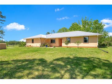 Lovely single-story home featuring a metal roof and a well-manicured lawn and a bright exterior on a sunny day at 140 Rodeo Rd, Ormond Beach, FL 32174