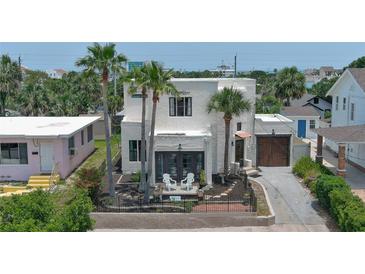 Charming stucco home with palm trees, wrought iron fence, and driveway at 145 S Peninsula Dr, Daytona Beach, FL 32118