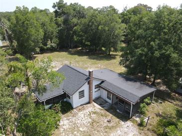 Aerial view of a single-story home with a dark roof, chimney and a yard with mature trees at 1880 N Sparkman Ave, Orange City, FL 32763