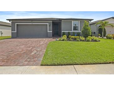 Charming one-story home with a well-manicured lawn, brick driveway, and beautiful landscaping at 460 Sarah Nicole Way, New Smyrna Beach, FL 32168