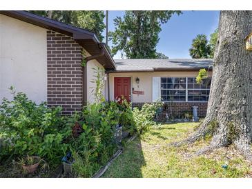 Charming home with a red front door, brick accents and lush landscaping welcomes you to this cozy abode at 5 Greenfern Cir, Ormond Beach, FL 32174