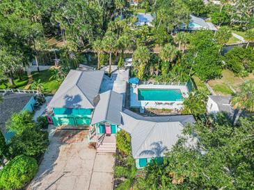 Stunning aerial view of turquoise home with lush landscaping, a private pool, and canal access at 61 E Bayshore Dr, Port Orange, FL 32127