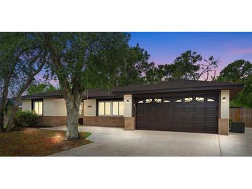 Charming single-story home featuring a large garage, brick accents, and mature trees at 1204 Lawrence Ave, Deltona, FL 32725