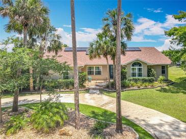 Inviting home featuring lush landscaping, a circular driveway, and solar panels on the roof at 1520 Stone Trl, Enterprise, FL 32725