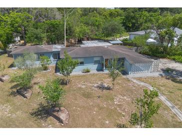 Charming, one-story blue home featuring mature landscaping and a unique decorative carport screen at 45 S University Cir, Deland, FL 32724