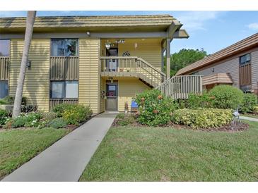Inviting condo exterior with a well maintained lawn, colorful flowerbeds, and staircase leading to the second floor at 600 N Boundary Ave # 118B, Deland, FL 32720