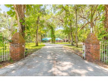 Long private drive leading to brick home surrounded by mature, moss-covered trees at 712 S Timberlane Dr, New Smyrna Beach, FL 32168