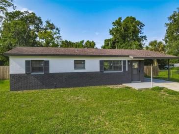 Charming single-story home boasts a gray brick and painted exterior, complemented by a lush green lawn at 1203 W 20Th St, Sanford, FL 32771