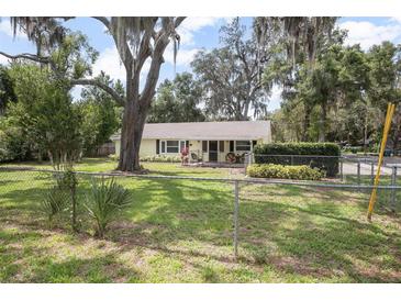 Charming single-story home featuring a well-maintained lawn and mature trees at 1402 E Voorhis Ave, Deland, FL 32724