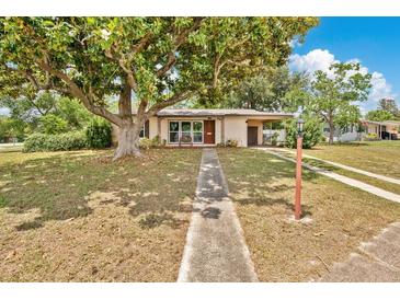 Charming single-story home with a walkway leading up to a covered porch, shaded by a large tree at 1610 Brady Dr, Deltona, FL 32725