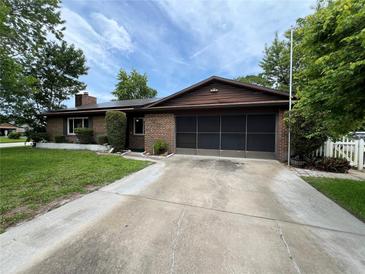 Charming single-story brick home with a well-maintained lawn and a screen-enclosed two-car garage at 180 Pine Grove Ct, Daytona Beach, FL 32119