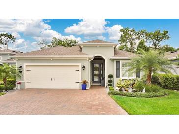 Charming home featuring a lush lawn, brick driveway, attached garage, and well-maintained landscaping at 241 Old Moss Cir, Deland, FL 32724