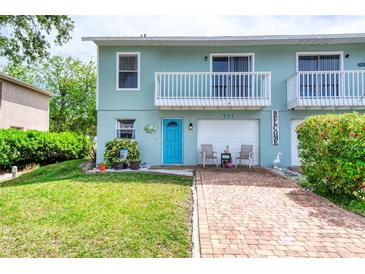 Charming two-story townhome featuring a light blue exterior, balcony, brick driveway and well-manicured lawn at 721 Laurel Bay Cir, New Smyrna Beach, FL 32169