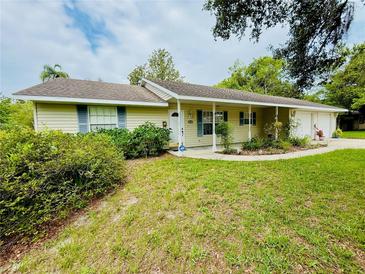 Charming single-story home with light yellow siding, blue shutters, covered porch, and well-maintained lawn at 733 E Ohio Ave, Deland, FL 32724
