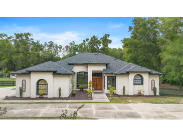 Stunning single-story stucco home featuring a symmetrical design, a concrete driveway, and manicured landscaping at 940 Glenwood Rd, Deland, FL 32720