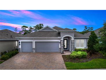 Charming single-story home with a brick driveway, three-car garage, and landscaped yard at 1227 Victoria Hills N Dr, Deland, FL 32724