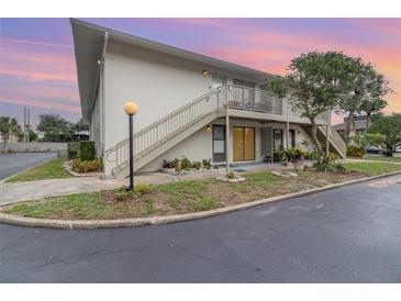 Two-story condo with a well-maintained lawn and landscaping in front of the stairway and porch at 1935 Conway Rd # A4, Orlando, FL 32812